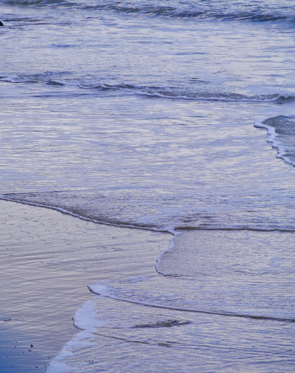 a person walking on the beach with a surfboard